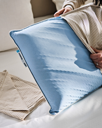 Blue pillowcase being placed over a pillow.