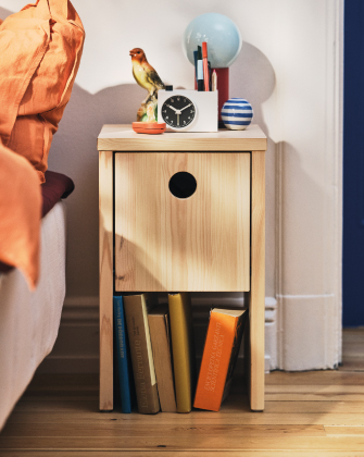 Wooden bedside table with books and a clock.