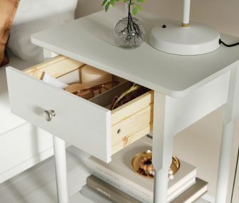 White bedside table with an open drawer and lamp.