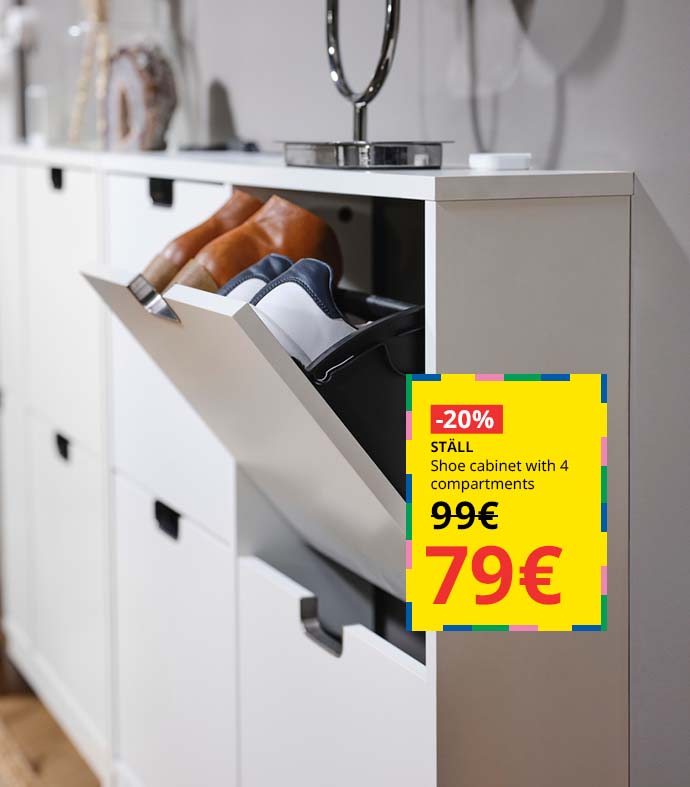 White shoe cabinet with a tilted compartment showing a pair of sneakers and a pair of ankle boots.
