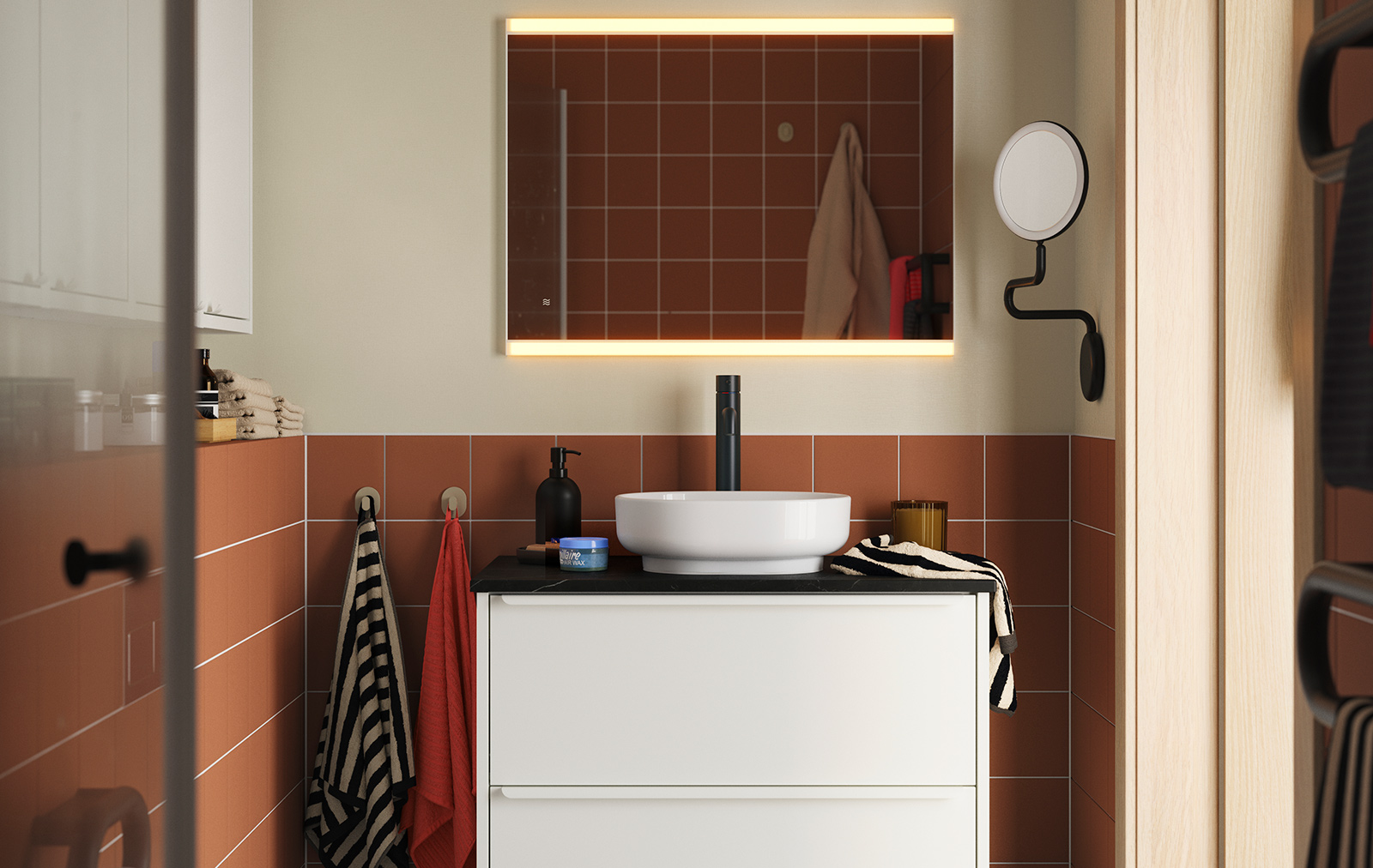 Un baño con azulejos de terracota, con un mueble de lavabo HAVBÄCK/VINDEÄLVEN en color blanco, rematado con un lavabo redondo y un grifo negro.