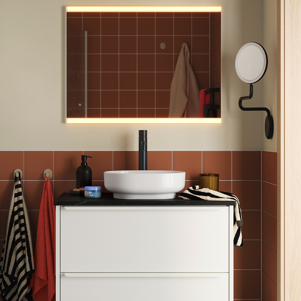 Un baño con azulejos de terracota, con un mueble de lavabo HAVBÄCK/VINDEÄLVEN en color blanco, rematado con un lavabo redondo y un grifo negro.