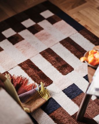 Modern living room with MARKBLÅMME rug and FLIKHAGTORN throw, showcasing bold geometric patterns