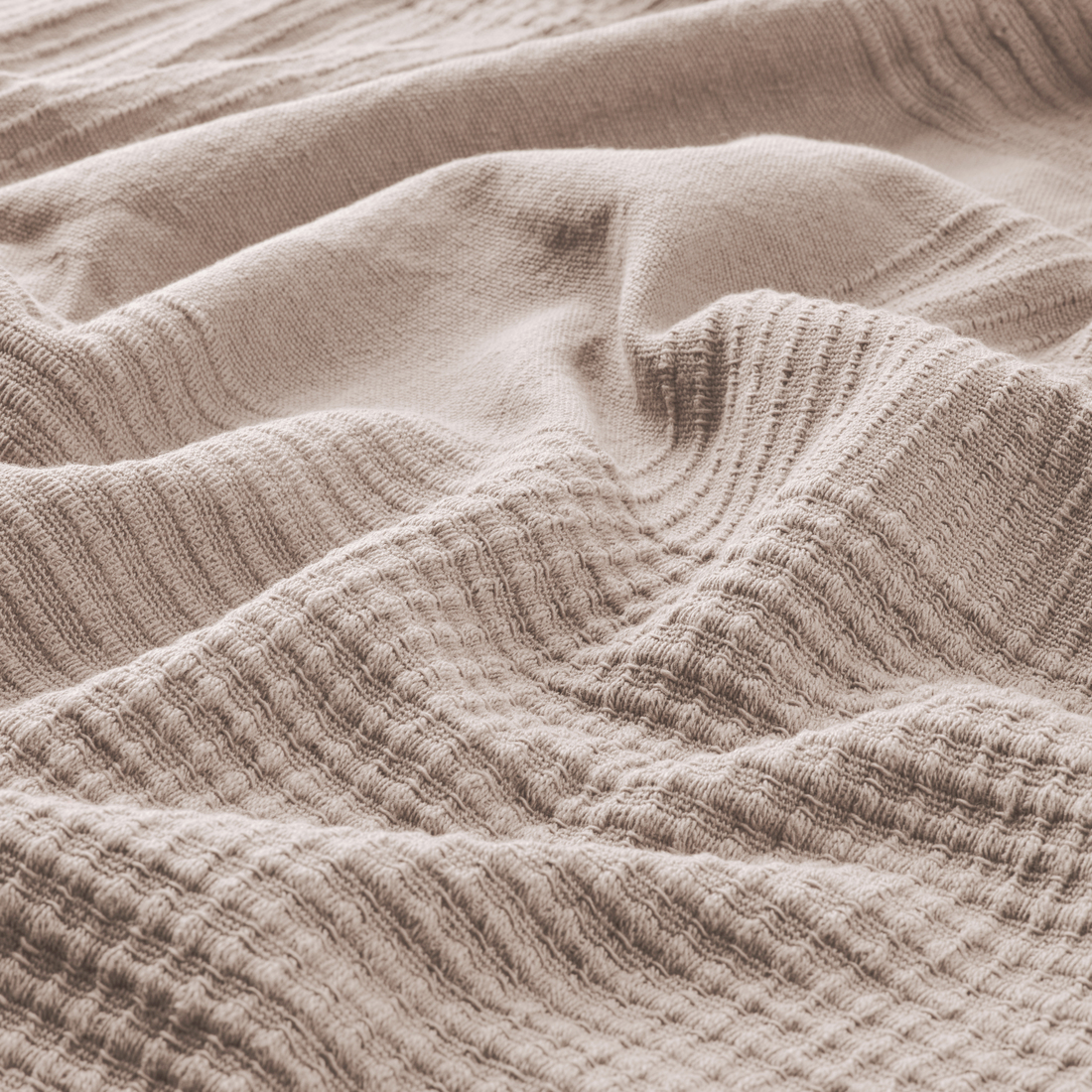 Colcha rosa con textura de ondas suaves.