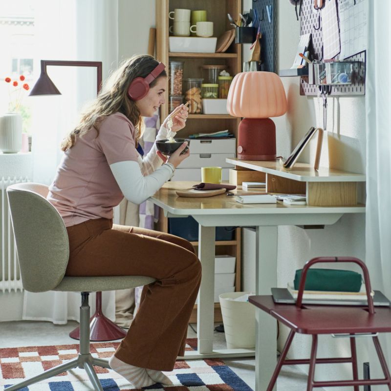 Dormitorio acogedor con mesa TRAVSPORT, silla giratoria KRYLBO, tablero SKÅDIS, librero BILLY y lámpara KULGLASS.