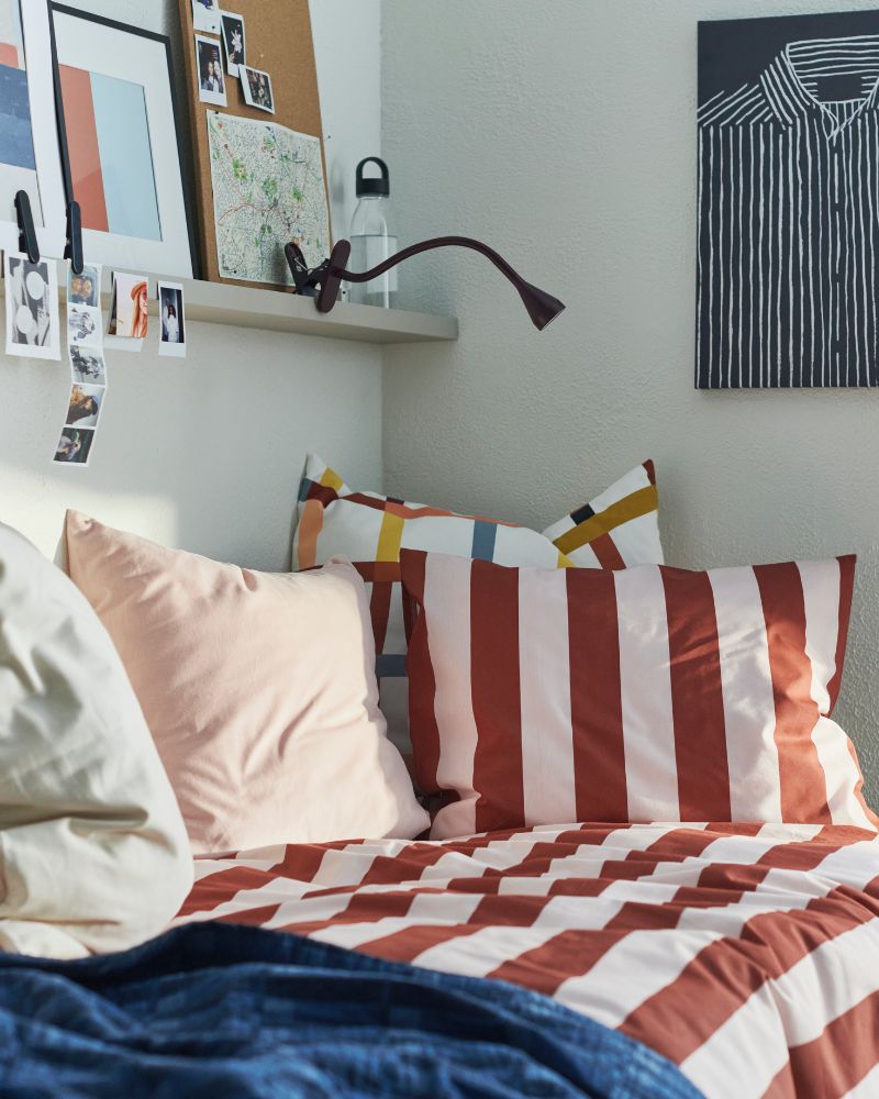 Dormitorio creativo con funda nórdica SLÅNHÖSTMAL, colcha SKOGSKOVALL, estante MOSSLANDA y lámpara NÄVLINGE.