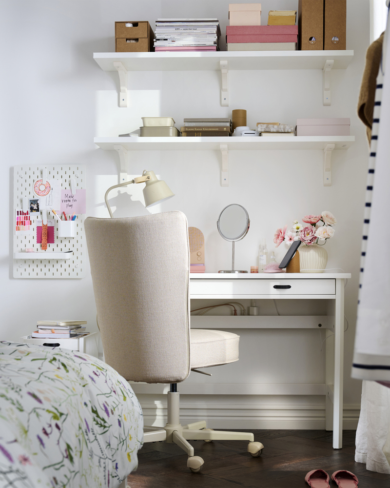 A study area featuring a white BERGSHULT wall shelf made from white stained aspen, neatly displaying stationery and decor.