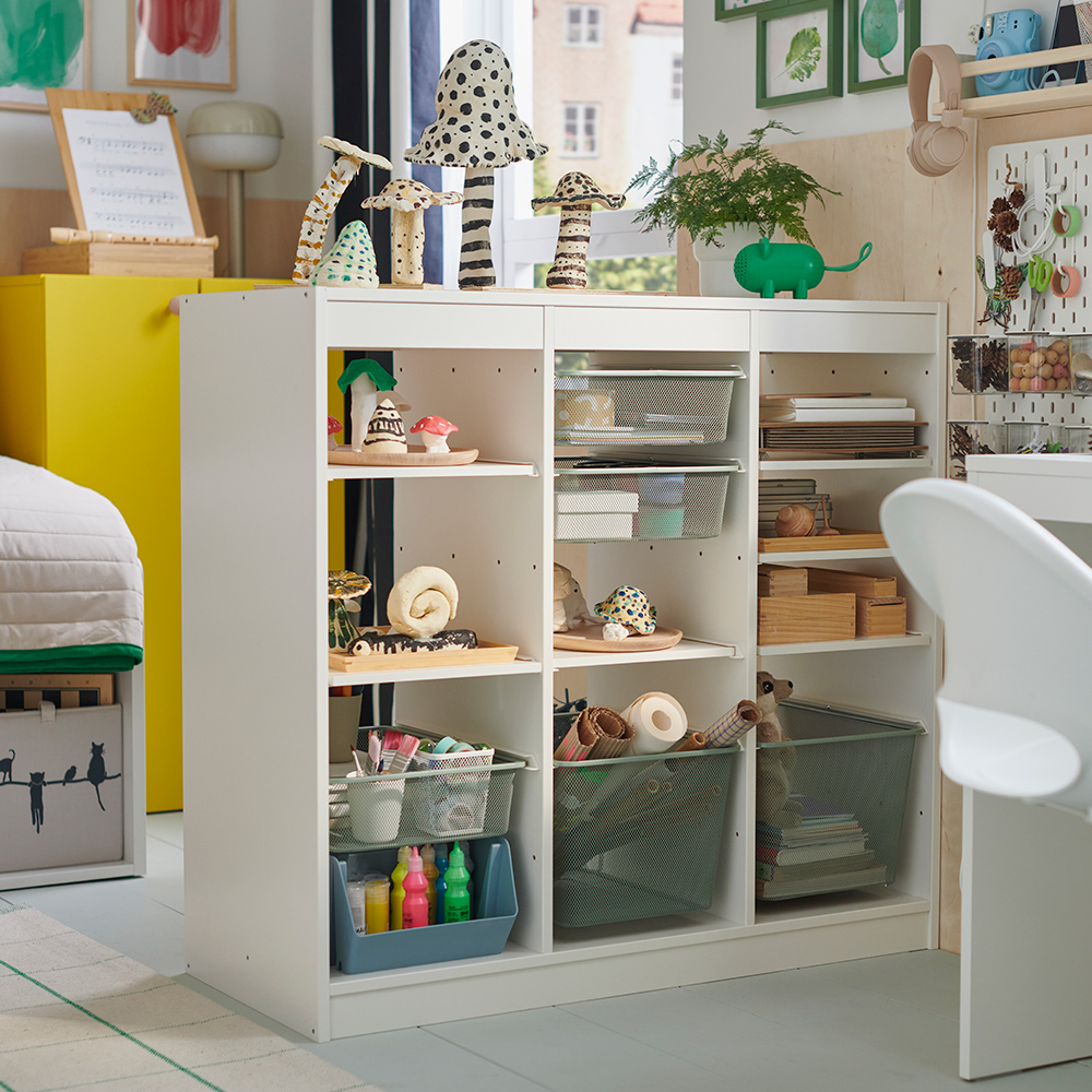 A child’s room features a white TROFAST storage combo filled with hobby supplies and completed craft projects.