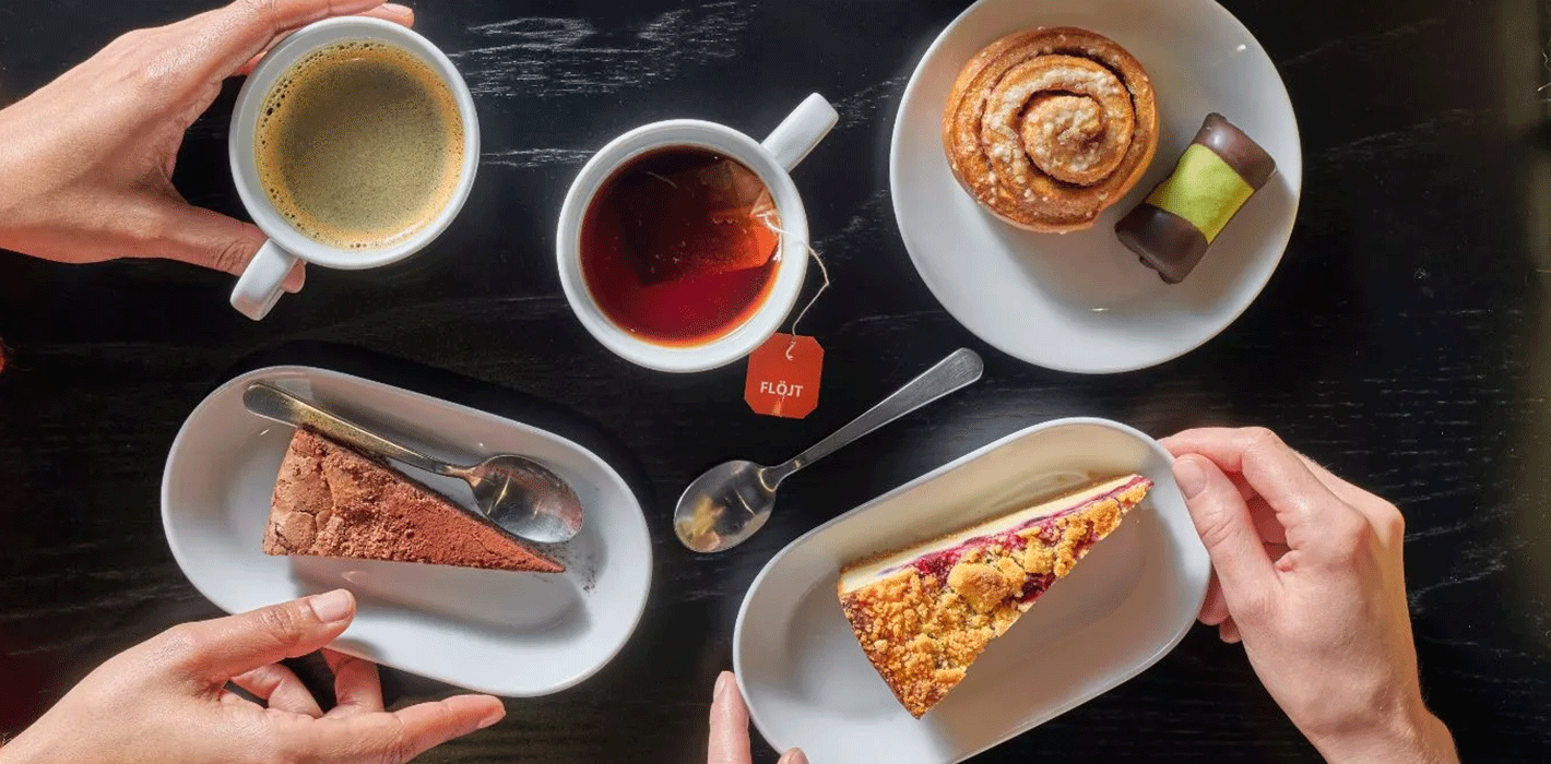 Pictured are coffee mugs, a teacup, a cinnamon roll, a chocolate cake, an apple-blueberry pie, and a white tray with the IKEA logo.