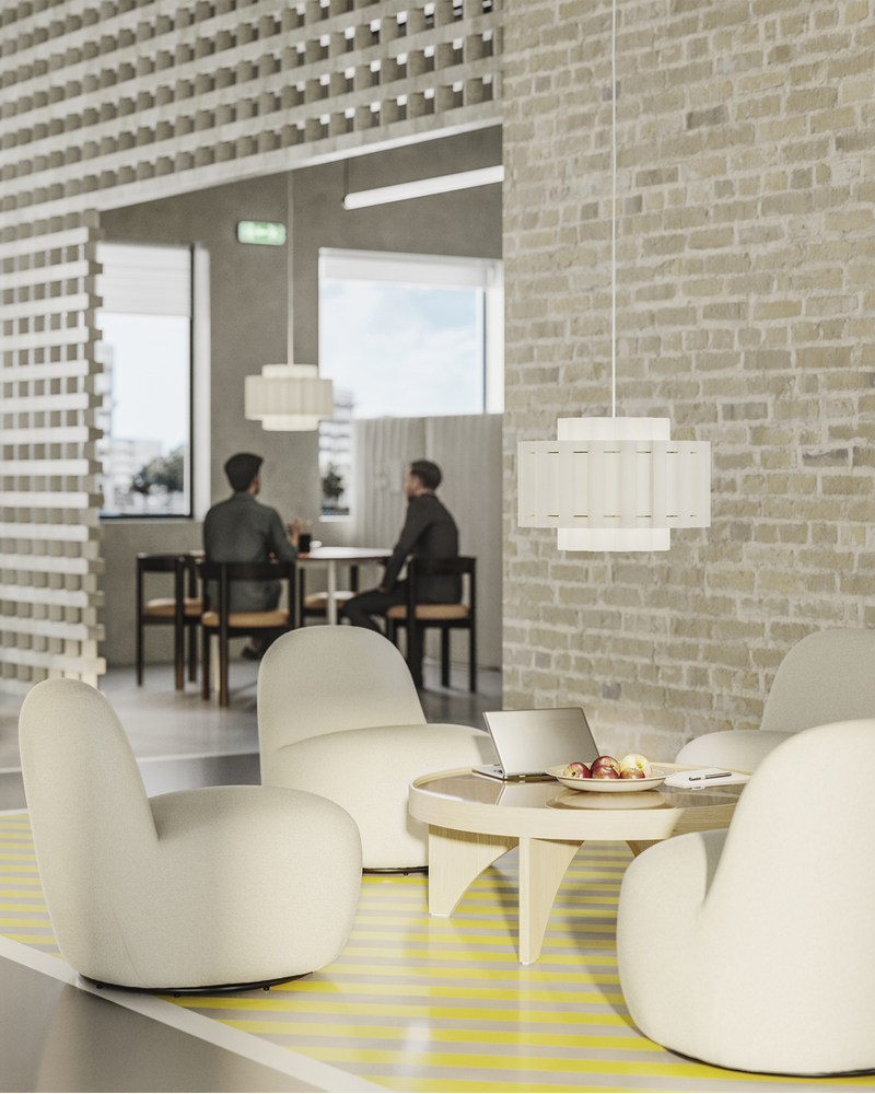 Cuatro sillones blancos alrededor de una mesa de centro, situados frente a la pared de ladrillo claro de una oficina diáfana.