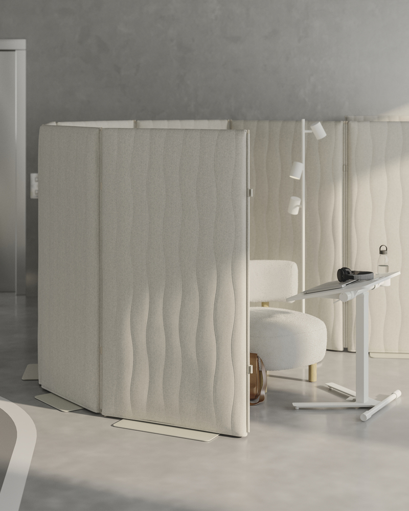 Zona tranquila para concentrarse en una oficina diáfana, con mamparas acústicas de pie, asientos cómodos y una mesa inclinada para el portátil.