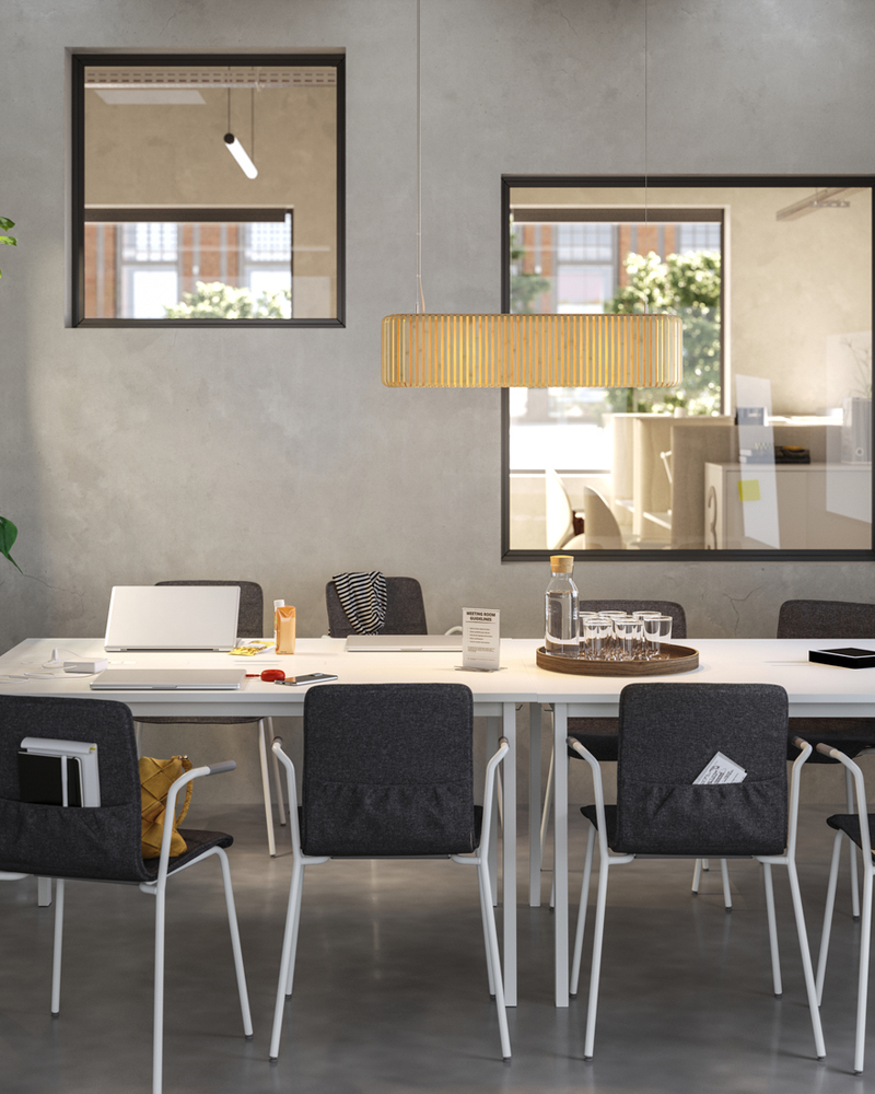 Sala de reuniones con un diseño sencillo y estilizado, con mesas blancas y sillas de conferencia tapizadas en negro.