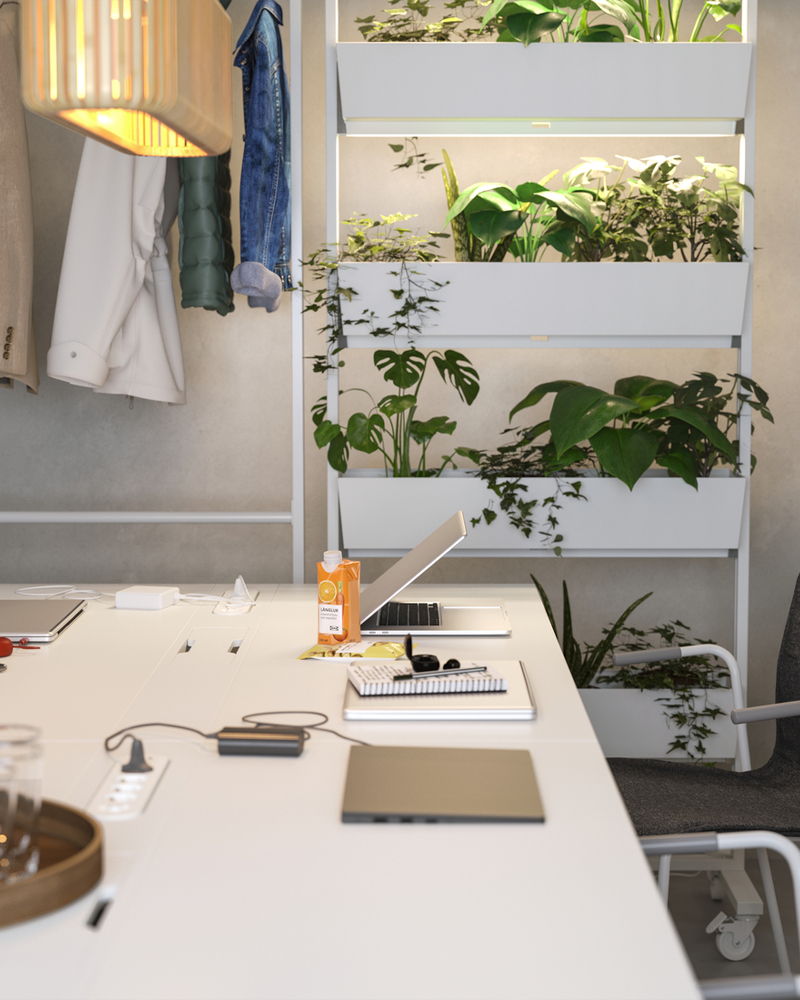 Mesa de reuniones con un compartimento para cargar ordenadores y teléfonos. La iluminación tenue y las plantas crean un ambiente acogedor.