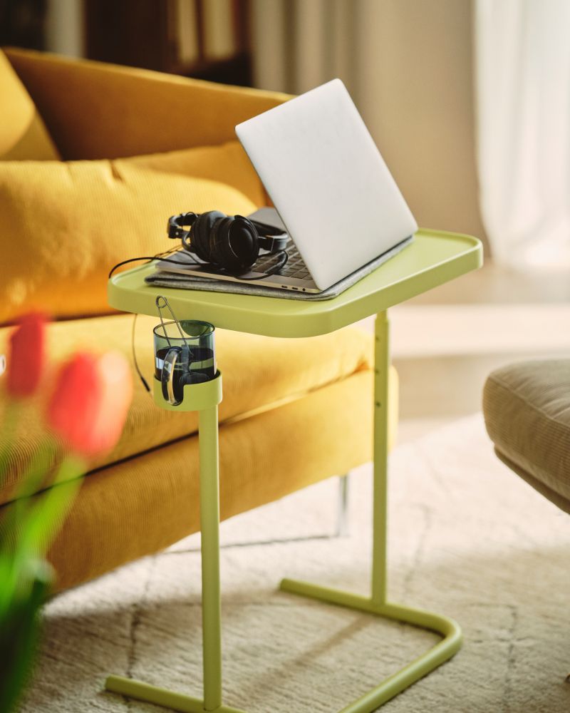 A yellow-green laptop stand next to a yellow sofa.