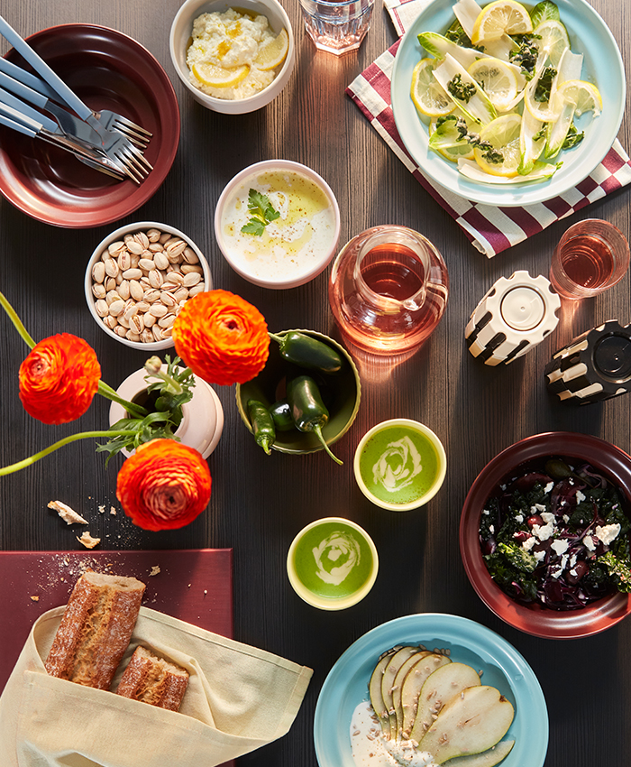 Mesa puesta con alimentos, bebidas y vajilla colorida de la colección SPJUTLILJA.