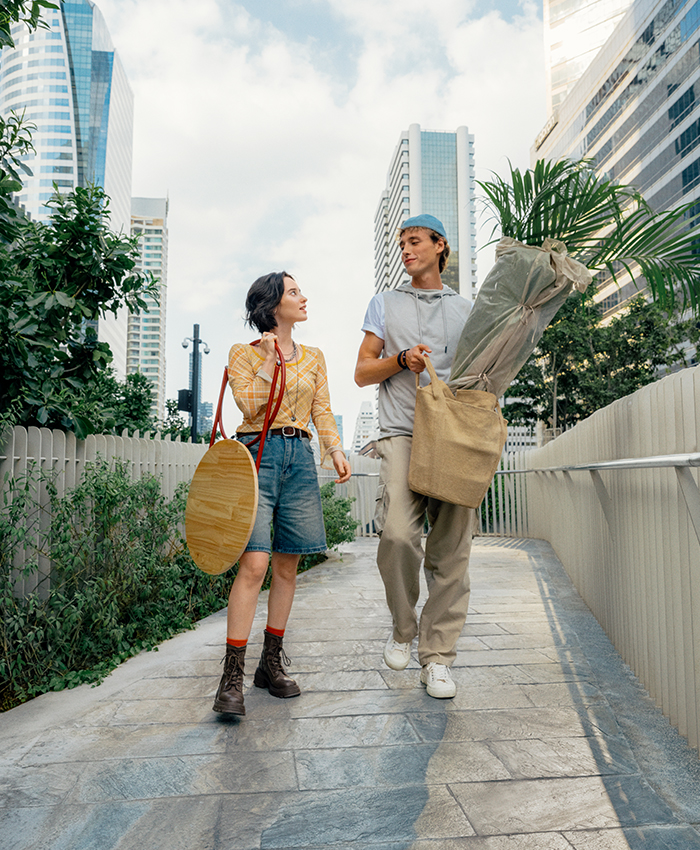 Two people walk through the city carrying a houseplant and home accessories on their way home to decorate a new space.