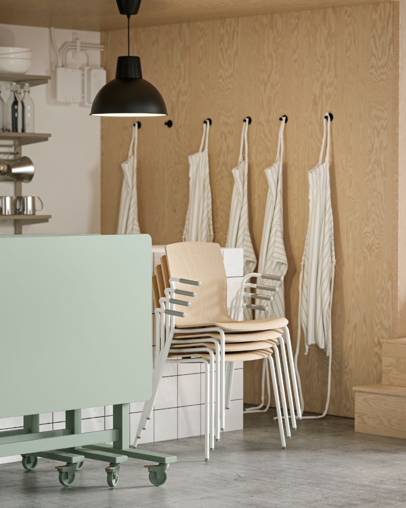 Four LÄKTARE conference chairs in birch veneer/white stacked against a counter, with green folded MITTZON tables beside them