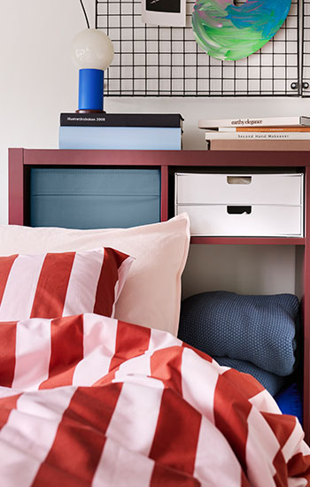 A bedroom with a blue DRÕNA box placed on a red shelf.