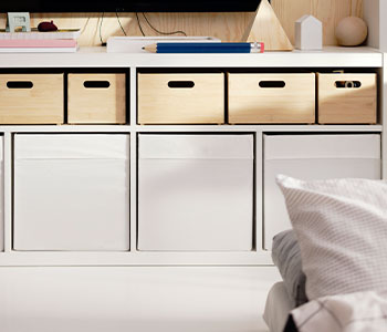 Different storage boxes on a shelf in a combined living and sleeping area.