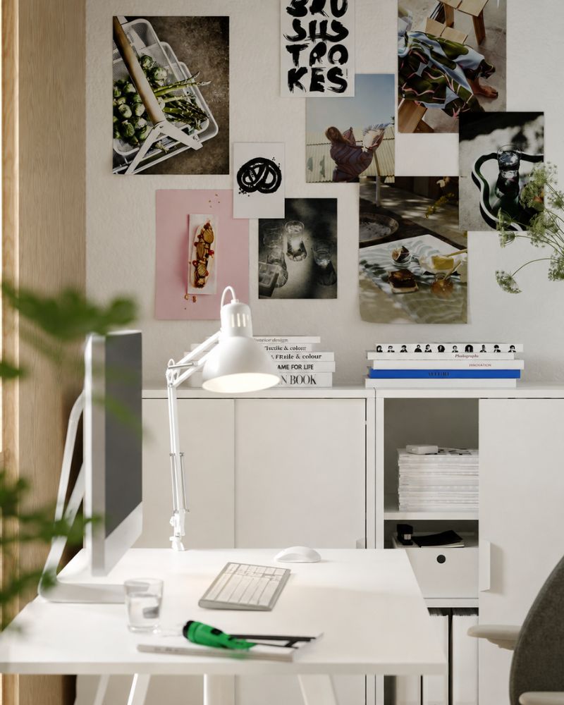 Two white TROTTEN cabinets with sliding doors, filled with magazines, standing side by side with a TROTTEN desk in the front.