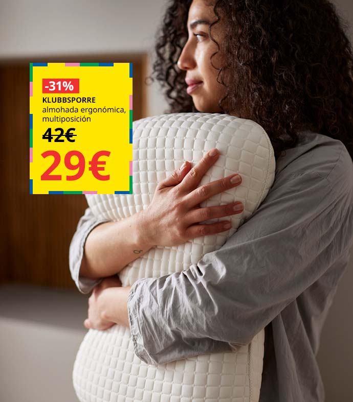 Mujer de pelo rizado abrazando una almohada ergonómica blanca con textura de cuadrícula mientras mira de lado.