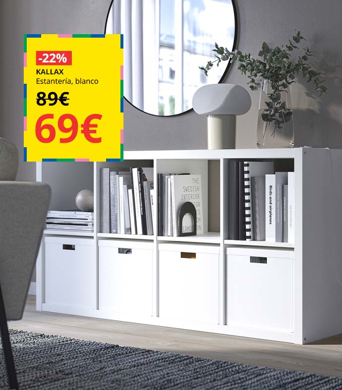 Mueble estantería blanco con libros y cajas organizadoras, un espejo redondo en la pared y una lámpara encima.
